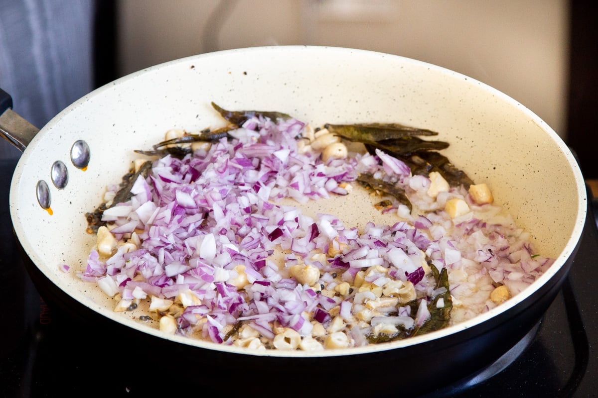 diced onion and tempered spices in a frying pan 